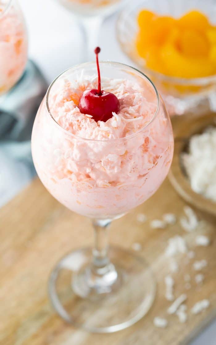 This creamy orange fruit salad is loaded with an easy combination of mandarin oranges, crushed pineapple, coconut flakes, and an orange-flavored cool whip mixture that's topped with maraschino cherries. Creamy Orange Fruit Salad