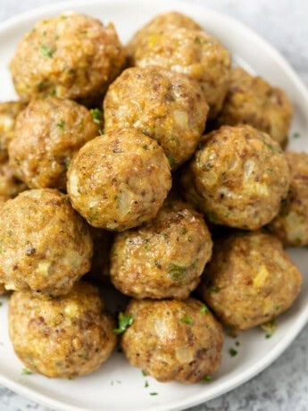 A pile of turkey meatballs on a white plate with parsley.