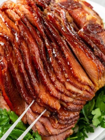 A platter topped with glazed ham on top of parsley.