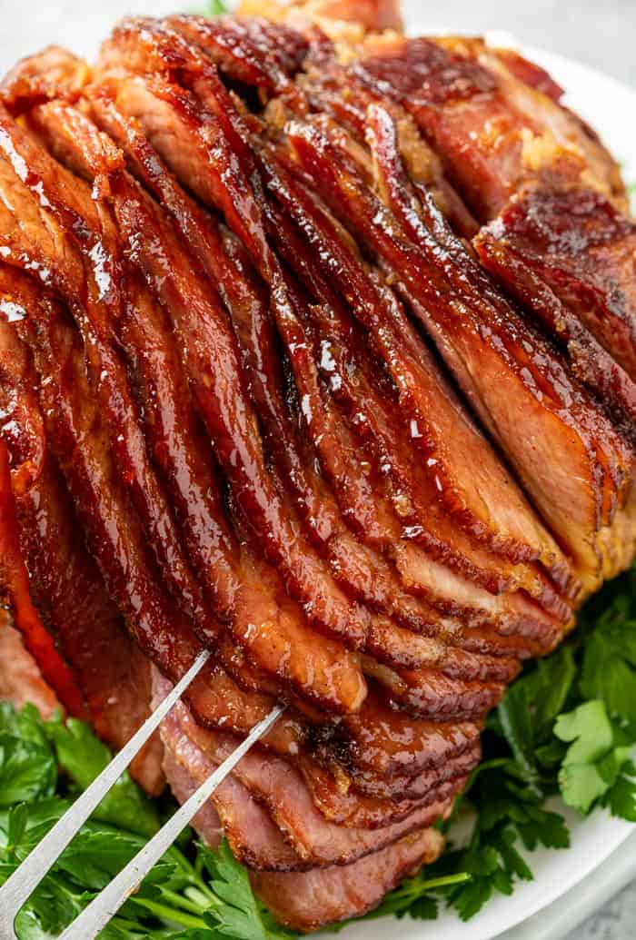 A platter topped with glazed ham on top of parsley.