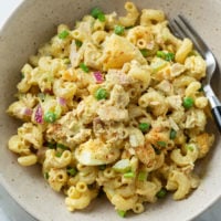 Tuna Pasta Salad with hard boiled eggs, onions, and peas in a bowl.
