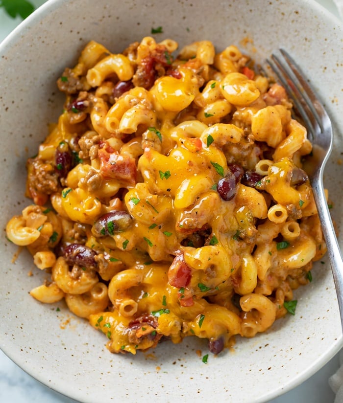 A bowl of Cheesy Chili Mac with a fork on the side.