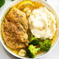 Pan Fried Chicken on a white plate with broccoli and mashed potatoes.