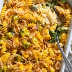 A creamy Chicken and Broccoli Rice Casserole in a white baking dish with a spoon scooping some out.